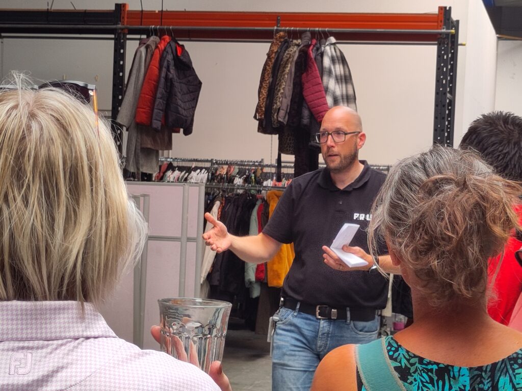 John Hinten legt uit in het Textielsoorteercentrum.